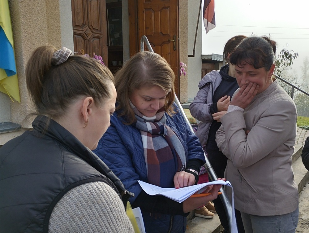 Інна Карвацька звіряє списки попередньої реєстрації на отримання гуманітарної допомоги.