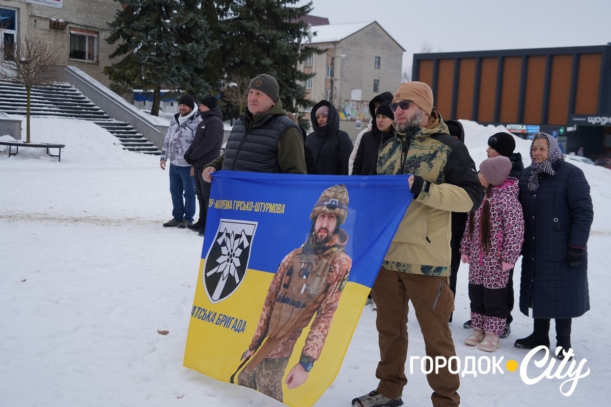 Віктор Скочеляс та Тимофій Мединський тримають стяг із фотографією загиблого Героя.