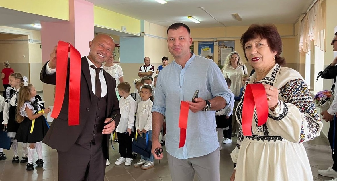 Під оплески учнів та батьків Катерина Пилипенко, Сергій Рибак та Артур Косінський розрізають червону стрічку.