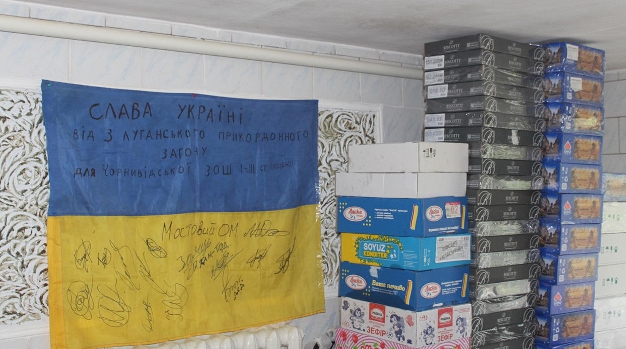 Прапор України з підписом Олександра Мостового, який зараз захищає Батьківщину.